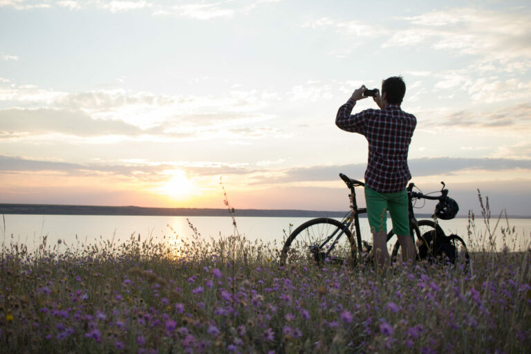 Mann fotografiert einen See mit Fahrrad